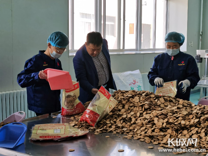 谭唤勇（中）在包装车间了解建档立卡贫困户王栋梁（左一）的工作情况。长城网记者 王林红 摄