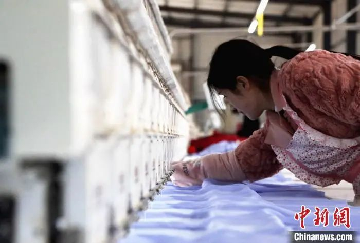 资料图：在菏泽市曹县大集镇的一家电脑绣花的厂房内，工人正在调整机器。　沙见龙 摄