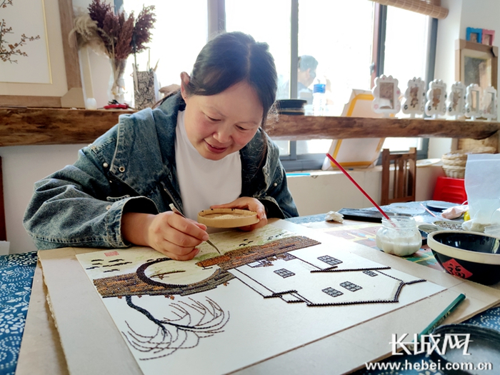 师献巧正在自家工作室里制作粮画。长城网记者 信贺宁 摄