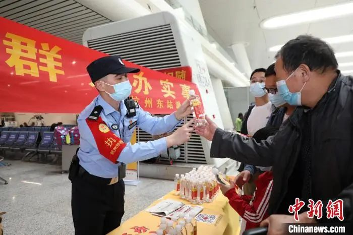 资料图：民警向旅客赠送印有反诈口诀的矿泉水。　韦士钊 摄