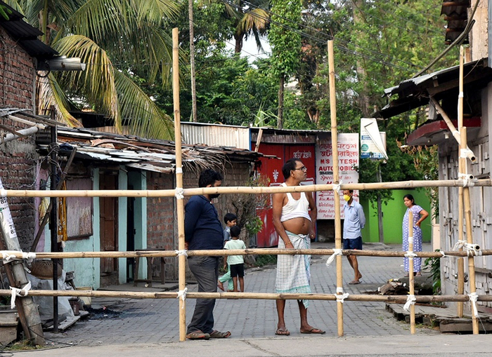  5月6日，印度高哈蒂一处隔离区的居民站在栅栏旁。