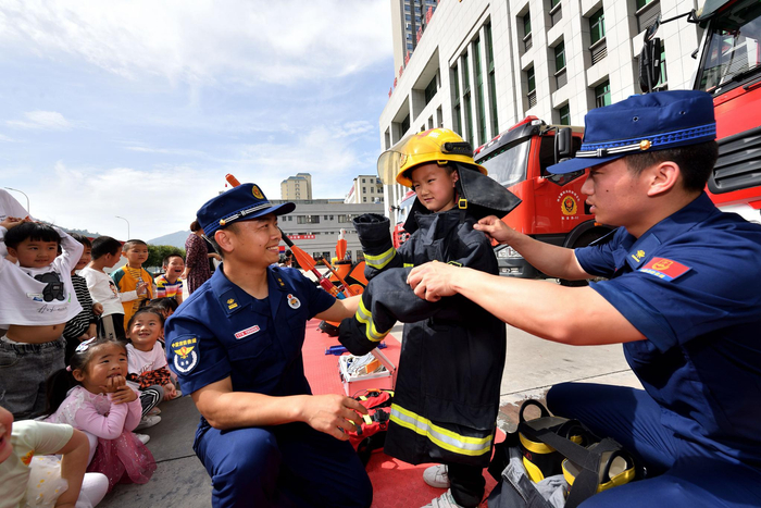 5月27日，湖北省襄阳市保康县消防救援大队队员帮助学生试穿消防灭火防护服。 图自澎湃影像