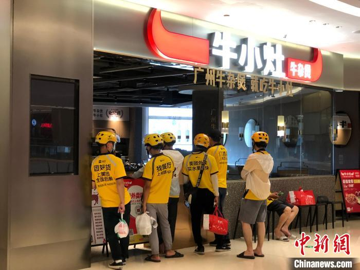 外卖配送员在海珠区保利广场一餐饮店门前等候取餐 孙秋霞 摄