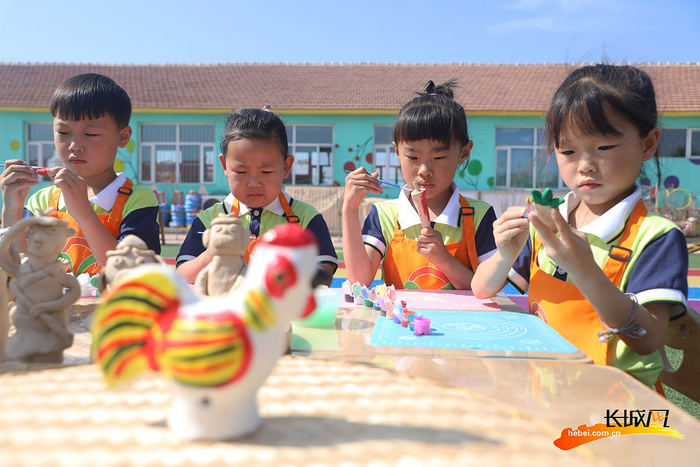 在唐山市丰润区白官屯镇燕子河幼儿园“非遗大集”上，小朋友们在给泥塑作品上色。朱大勇 摄