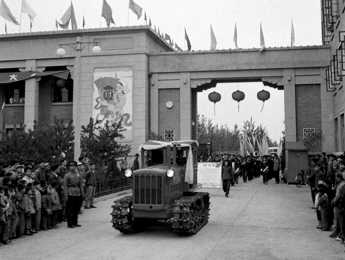 中国第一代拖拉机身披红花彩绸，“轰隆隆”开出中国一拖厂区大门，两旁挤满了围观群众（中国一拖集团有限公司供图）