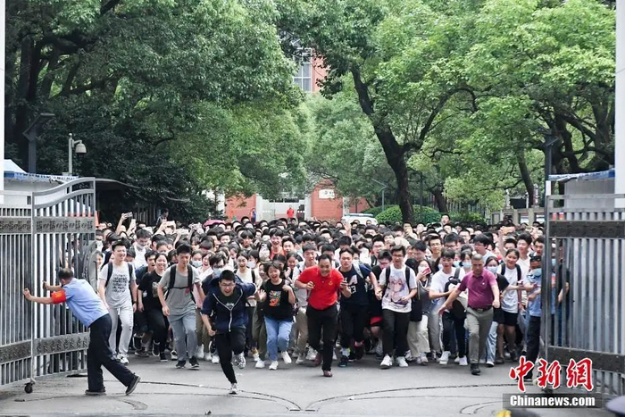 资料图：6月9日，考生与老师一同冲出长沙市一中考点。 中新社记者 杨华峰 摄