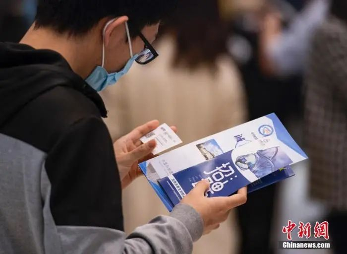 资料图：一名学生在查看招聘单位联系人的名片。中新社记者 侯宇 摄