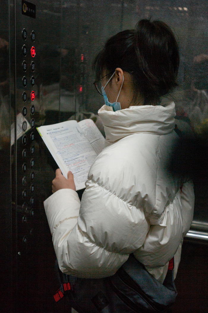 2021年4月3日，济南某小区住宅楼，一上初中女孩乘电梯时还在看英语课本。图据视觉中国