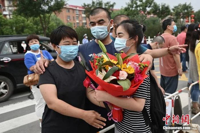 资料图：2020年高考结束，一名考生走出考场后与家人相拥。 中新社记者 张兴龙 摄