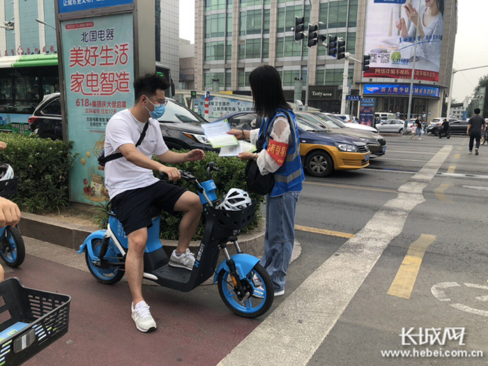 志愿者正在路口为行人派发文明出行倡议书 王玉娇 摄