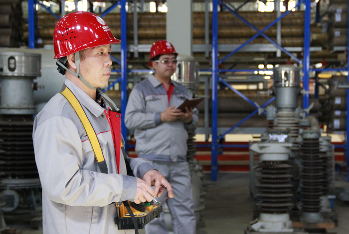 国网冀北电力物资公司人员在绿色仓库操纵行车起重设备的遥控装置进行作业。（刘云菲 摄）