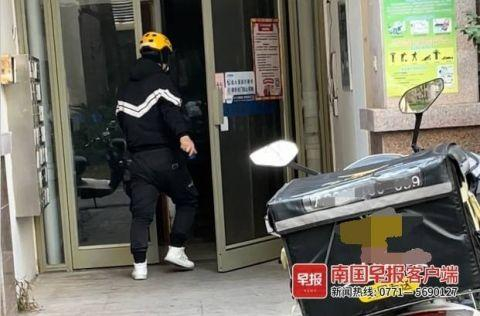 ▲外卖小哥手拿蓝色门禁通卡进出小区单元楼。南国早报客户端见习记者 罗贝尔 摄