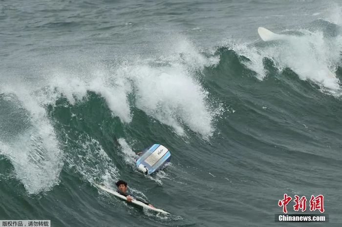 当地时间1月15日，在汤加发生海底火山喷发后，美国国家气象局发布了针对美国整个西海岸的海啸警报。图为美国国家气象局发布海啸警报后，冲浪者在加州海边冲浪。