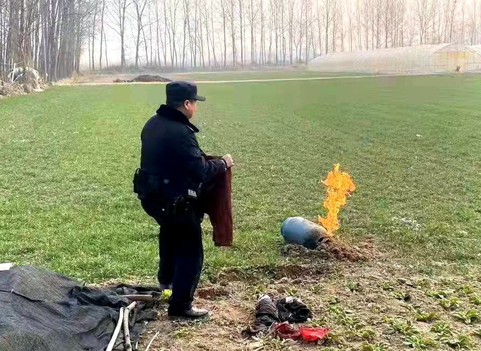 图为民警正使用湿毛巾准备扑灭燃烧着的液化气罐。