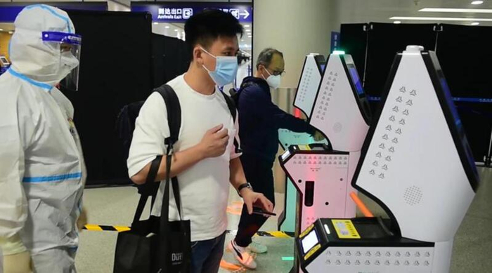 海关关员引导入境旅客通过多功能分流机完成测温，并根据风险高低实现精准分流。（姜森文 摄）