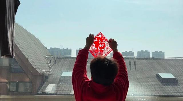 2022年1月31日，李芳在屋内的玻璃墙上贴福字。新京报记者 陈亚杰 摄