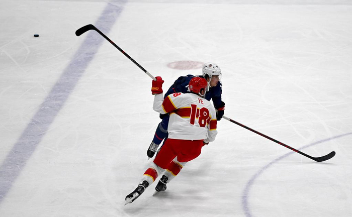 2月10日，中国队球员叶劲光（前）在冰球男子小组赛中。新华社记者刘潇摄