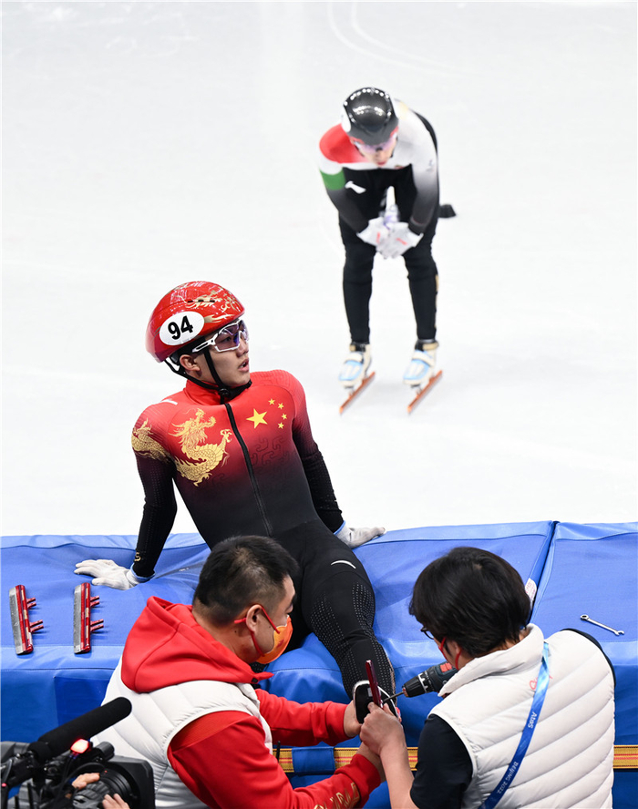 2月7日，中国队成员在比赛中为李文龙（前上）检查冰刀。 新华社记者李尕摄