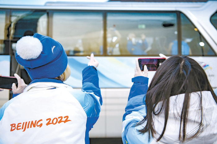 2月11日，在运动员班车场站，志愿者隔窗比心送别乌克兰运动员。张一林摄