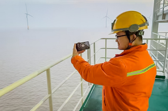 国家能源集团国华投资江苏海上风电员工在工作空隙，利用手机观看开幕会。  周鑫 摄