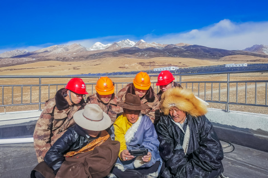 在海拔4300米的国家能源集团龙源电力西藏羊八井光伏电站，生产一线的电力员工正在通过手机观看开幕会。王文媛 摄