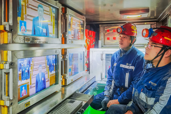 在离地面100米的国家能源集团神东煤炭寸草塔煤矿掘锚二队工作面，矿工利用休息时间观看开幕会。冯辉 摄