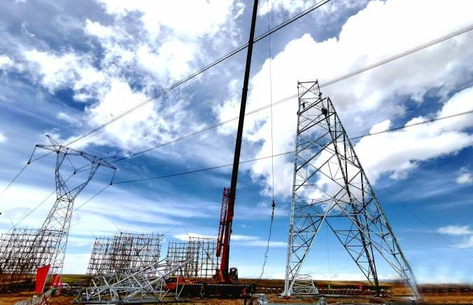 图为青海送变电施工人员在𝜋接施工现场对新组立铁塔进行吊装作业。 邹建华 摄