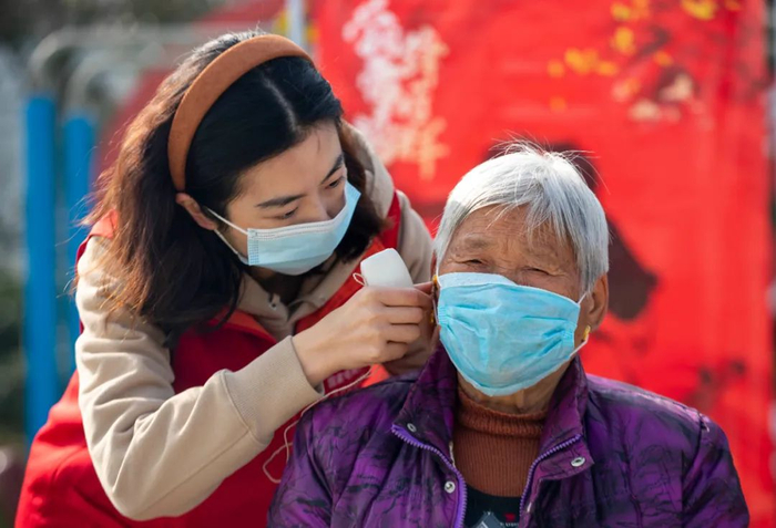 志愿者为老人佩戴免费的助听器。新华社发（汤德宏摄）