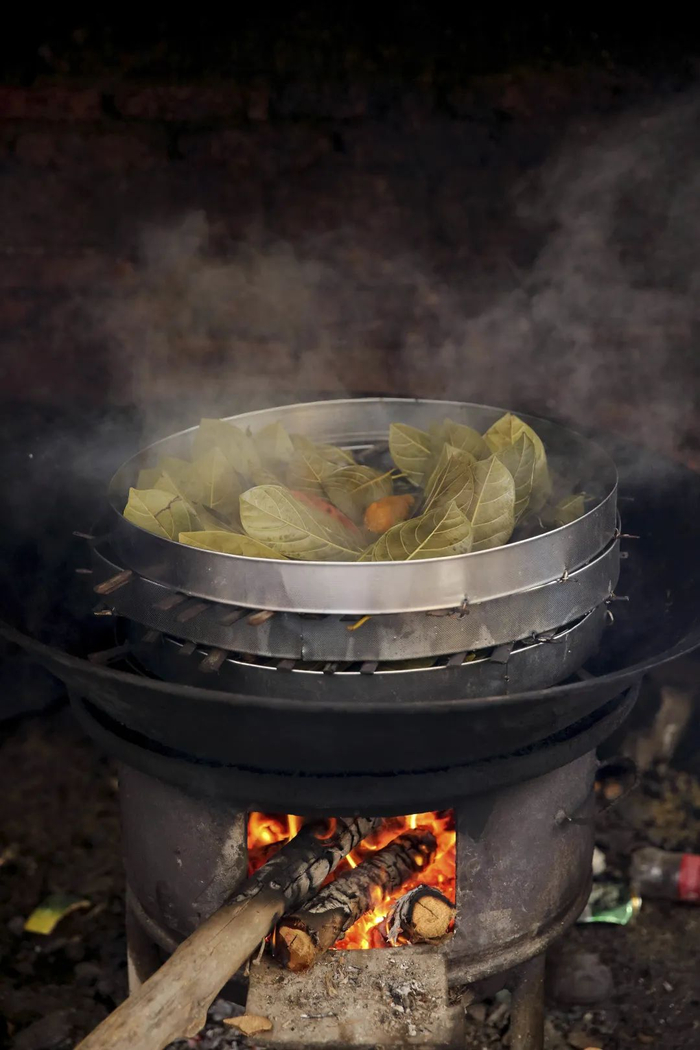 ▲正在蒸制的“树叶搭”，菠萝蜜的叶子赋予了食物清香（张雷 摄）