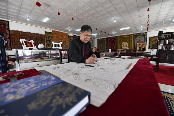 在河北省廊坊市文安县华盛宫毯坊，宫毯织造技艺非遗传承人周子华正在绘制样稿。王晖摄