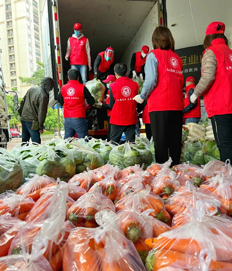 志愿者们冒着雨接力将爱心蔬菜卸下。 洛江区委文明办 供图