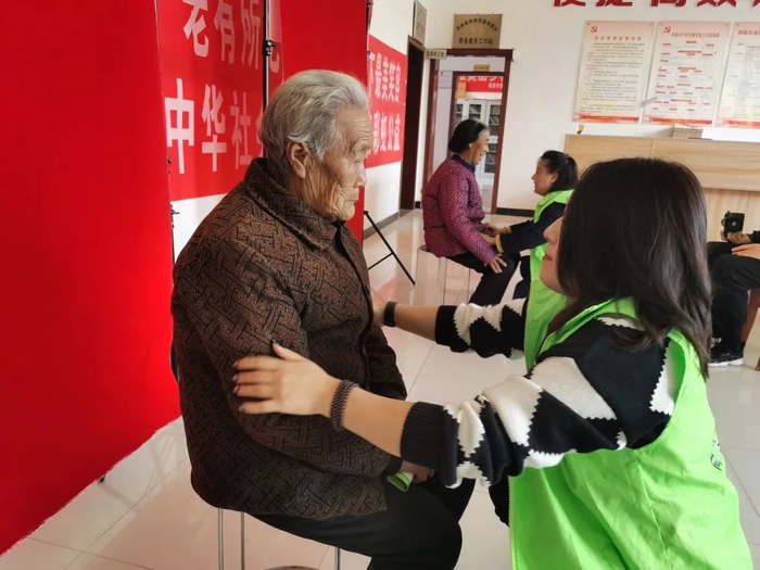 摄影师杨鑫帮拍照的老人调整坐姿。受访者供图
