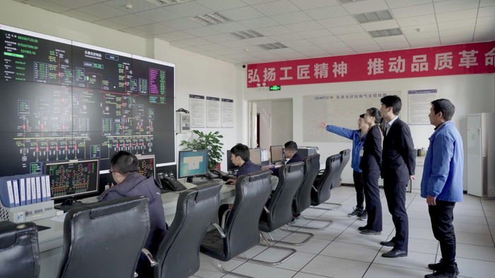 图为：民生银行温州分行客户经理在正泰集团数据智控车间查看光伏电站数据