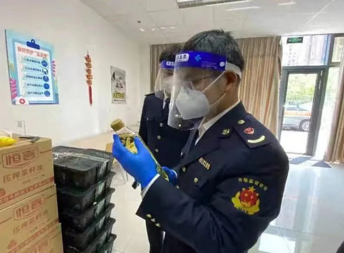 ↑图为区市场监管局正在对该批次下发的食用油进行核查