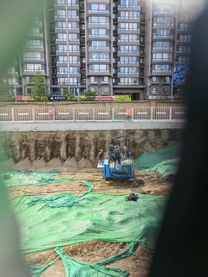 透过遮挡板的缝隙可见工地内有人正在施工。 于丽丽 摄