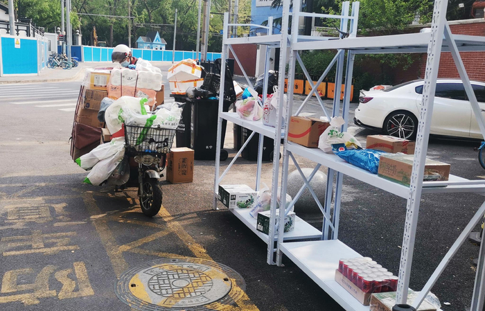 骑手为一封闭社区居民送网购物资货品 图/视觉中国