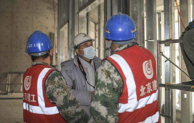 王建忠（中）在工地上与工人交谈，了解施工情况。  新京报记者 浦峰 摄