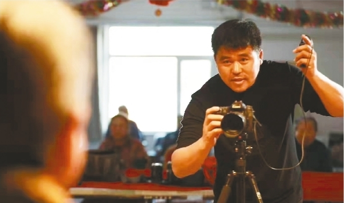         刘国壮为敬老院老人拍照。图片由受访者提供