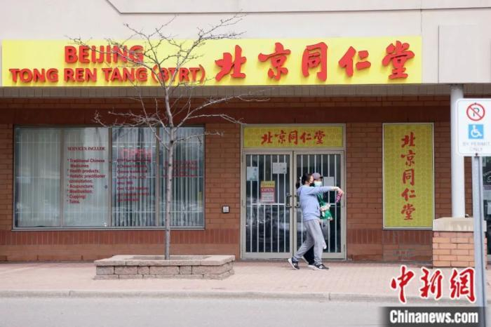 行人从一家知名中药店加拿大多伦多连锁分店门前经过。中新社记者 余瑞冬 摄
