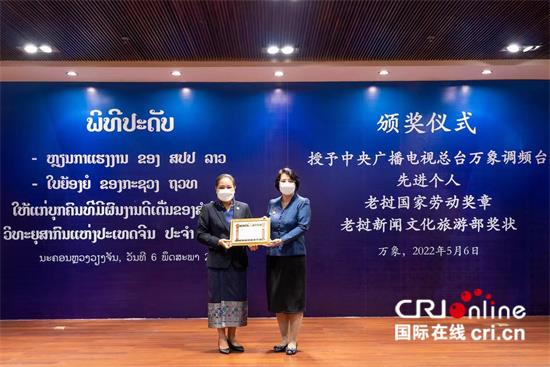 △老挝新闻文化旅游部部长宋莎婉（左）为总台万象调频台FM93总监莫小玲颁发奖状