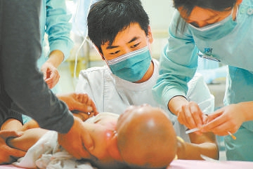 　　2011年，积水潭医院急诊科抢救室里的男护士在照顾被开水烫伤的患儿。戴冰/摄