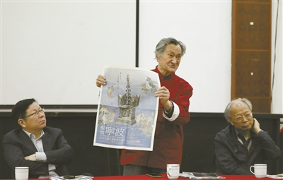     杨古城（左）在展示报纸上的展览海报。