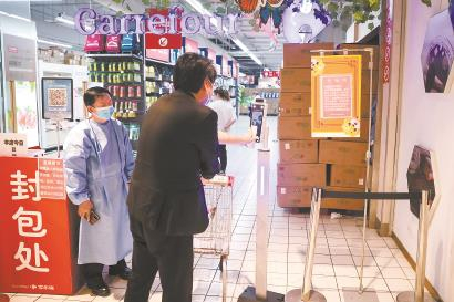 5月16日，在家乐福宜山店，工作人员在入口处提醒进店的市民打开随申码扫一扫“数字哨兵”。本报记者海沙尔摄