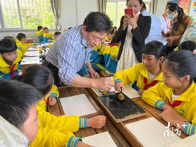  在专业拓印人员吕佩勇的指导下，所城镇中心小学的学生们手拿刷子，开启拓印“初体验”。受访者供图