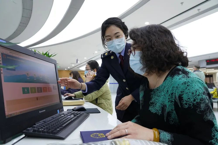 图为国家税务总局北京市西城区税务局工作人员辅导纳税人完成办税操作。