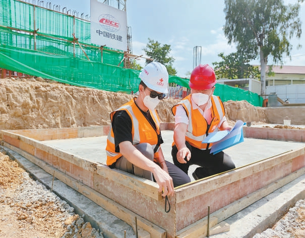 中国师傅冯登（右）正在教老挝籍徒弟言希检查模版尺寸。 郭鑫摄