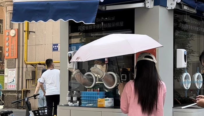 采样人员需将右手臂旋转45度才能触发自动感应手部消毒液机 陈月芹/摄