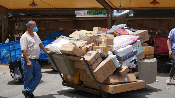 6月8日，上海市闵行区一处快递网点，一名快递员在用平板车运送快递。新华财经记者 杨有宗 摄