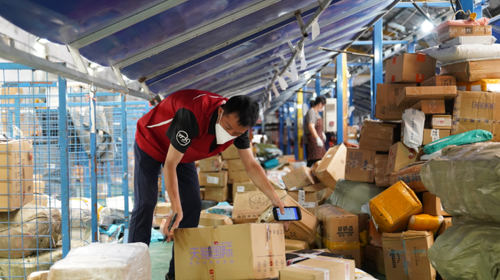 6月8日，上海市闵行区一处快递网点，一名快递员在进行包裹分拣。新华财经记者 杨有宗 摄