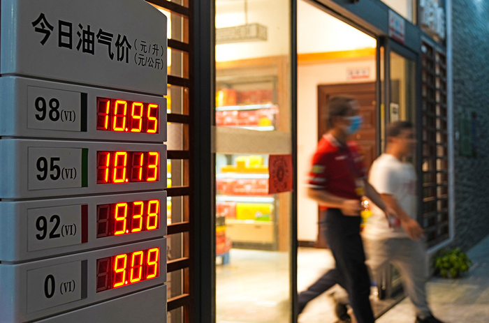 2022年6月14日，在广西柳州市融水苗族自治县一加油站，顾客从刚刚更新的汽油和柴油牌价前走过。